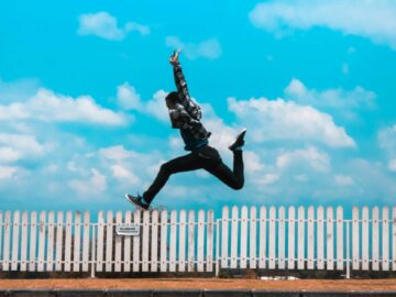 man jumping over white fence